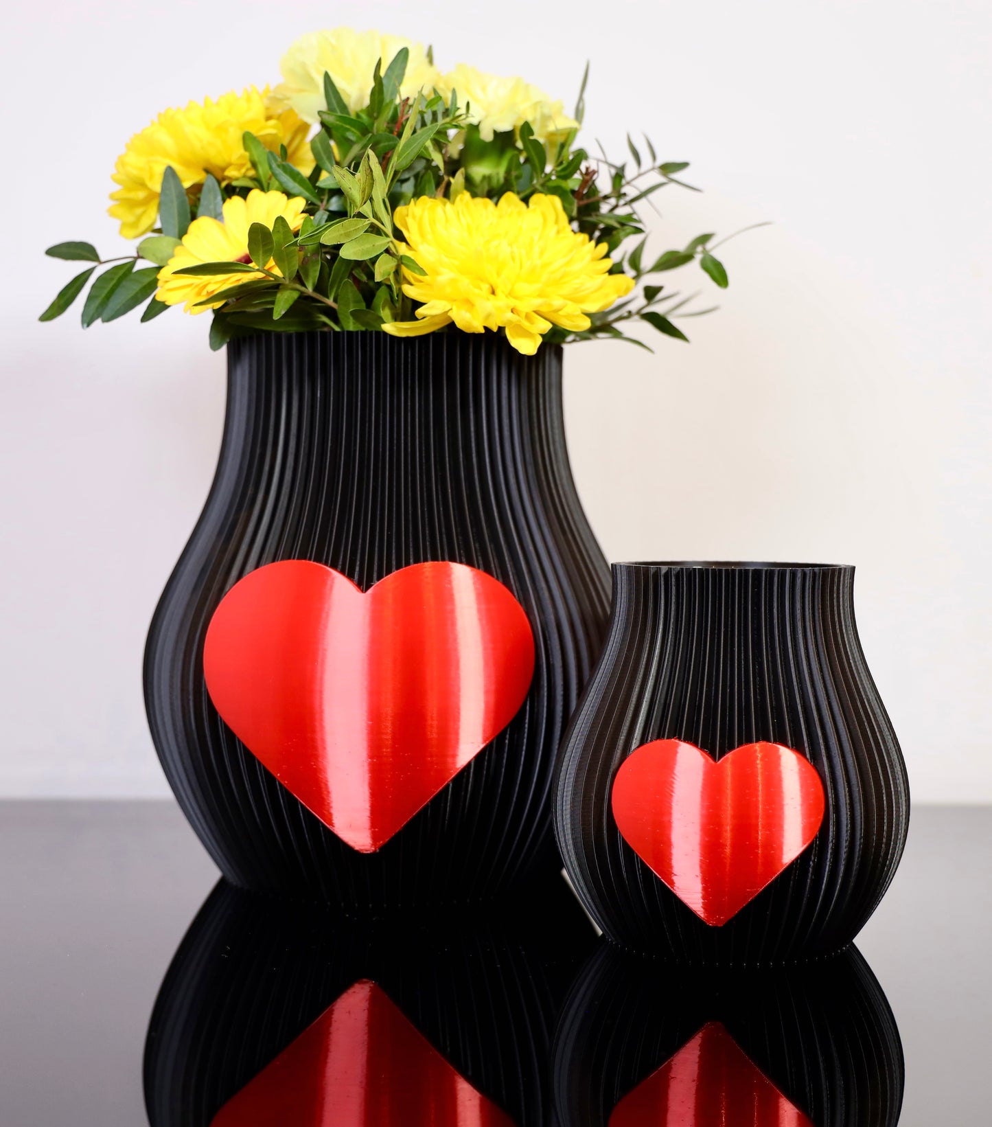 Schwarze 3D-gedruckte Designvase von Wälder Create mit rotem Herzmotiv, dekoriert mit Blumen – gefertigt im Bregenzerwald.