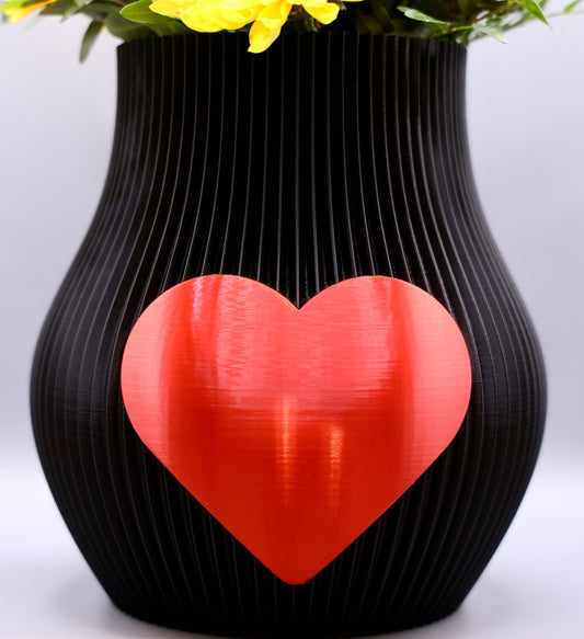 Schwarze 3D-gedruckte Designvase von Wälder Create mit rotem Herzmotiv, dekoriert mit Blumen – gefertigt im Bregenzerwald.