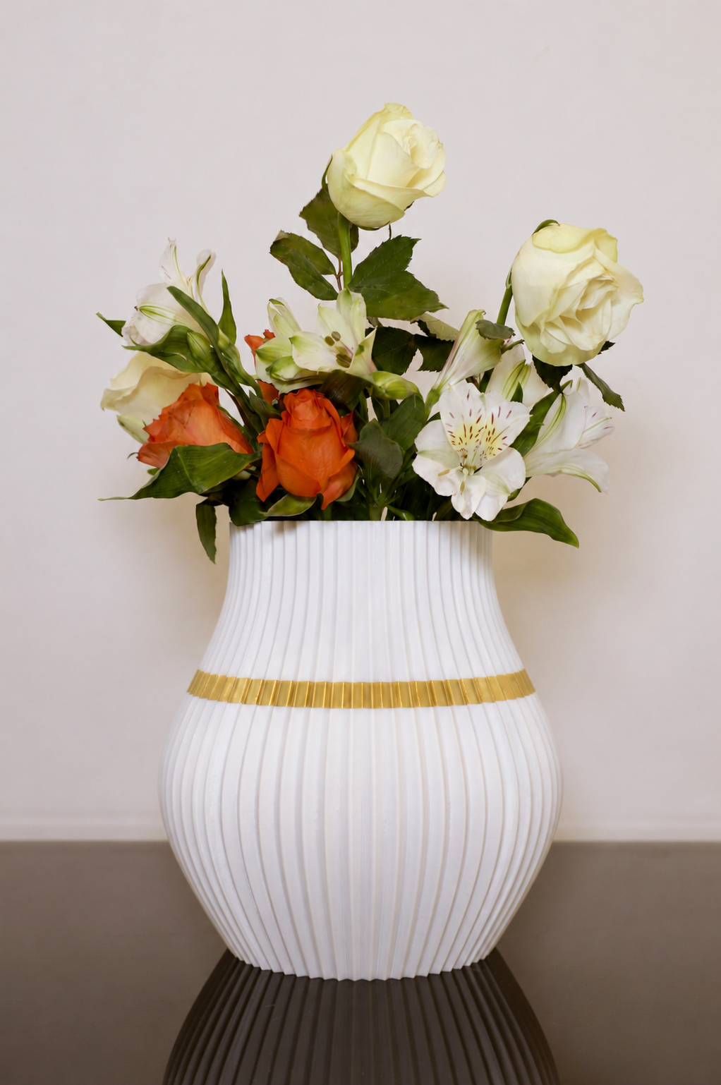 Moderne weiße Designvase mit goldenem Akzent und frischem Blumenstrauß aus weißen und orangefarbenen Rosen. Dekorative 3D-gedruckte Vase im stilvollen Wohnambiente.