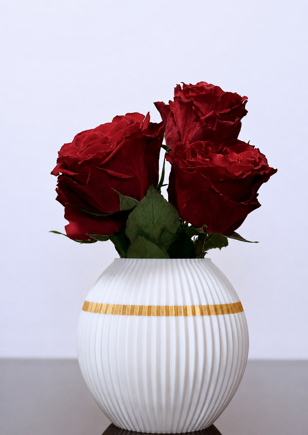 Elegante weiße 3D-gedruckte Vase mit goldenem Akzent und roten Rosen. Stilvolle Blumenvase als dekorativer Blickfang für Wohn- und Essbereiche.